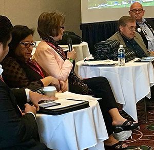 Linda Aitken, seated at a table, speaks to National Congress of American Indians.